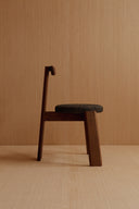 Side view of the chair, showing its angled wooden legs and dark fabric seat.
